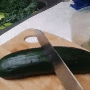 a cucumber being cut with a large knife