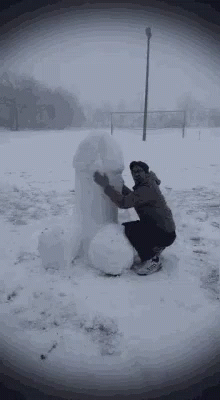 a man building a snowman in the snow