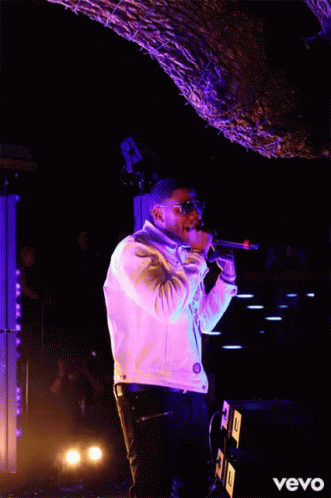 a young man singing into a microphone on stage