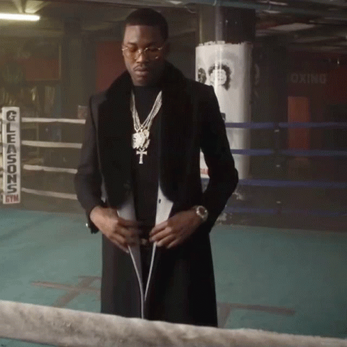 a man wearing a necklace standing by a boxing ring