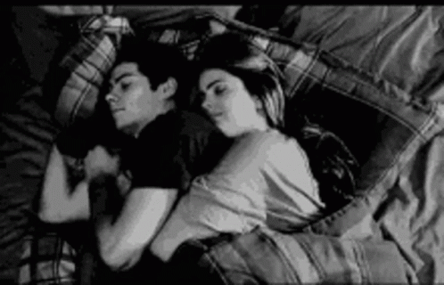 a young couple laying under a blanket in bed