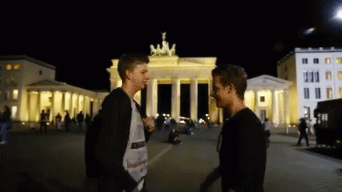two boys talking in front of an illuminated white monument