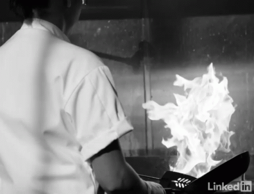 a kitchen staff working on a meal in flames