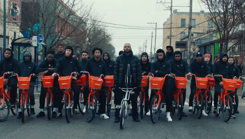 a group of people with fake faces and makeup on their face, standing behind blue bikes that are in front of an intersection