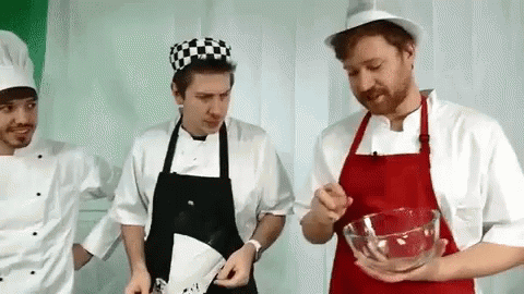 three men standing next to each other in chef hats and aprons