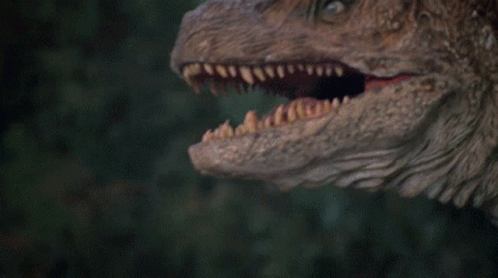 close up view of an adult t - rexe in front of trees