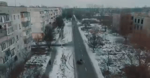 the aerial view of an empty city street with buildings and snow covered roads