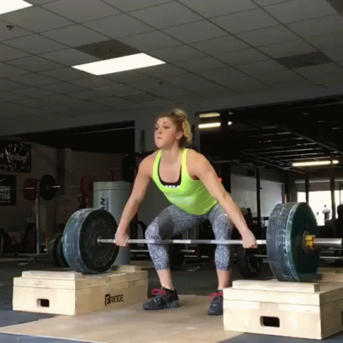 a woman squats on a box in the gym