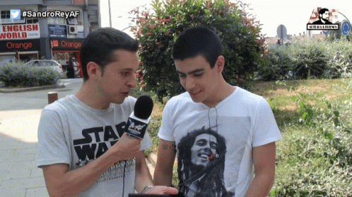 two people stand by each other on the street while one of them is holding a microphone