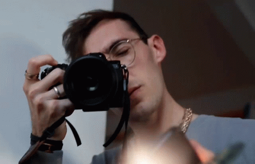 a man in glasses taking a picture with a camera