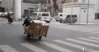 a person hing a luggage cart down a street