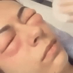 a person lying down in a bed with their eyes closed