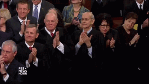 several men are in suits clapping for an audience