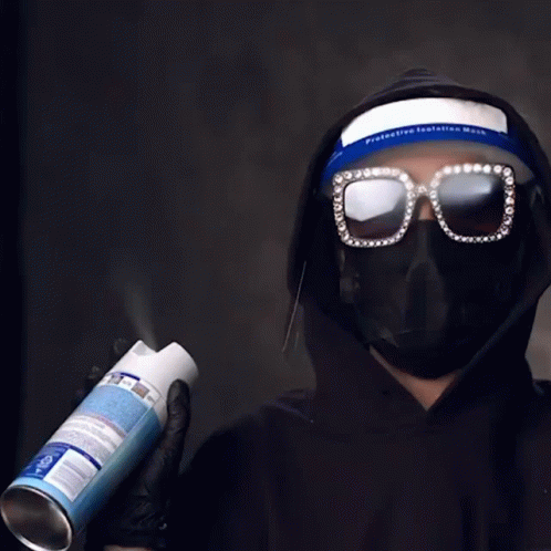 man in black hoodie and sunglasses holding up tube of oil
