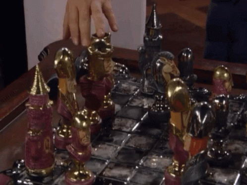a hand is moving the silver chess board