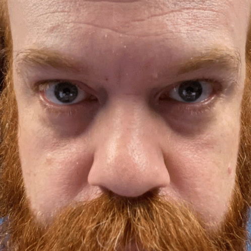 close up of a blue bearded man's face with facial hair and facial expressions
