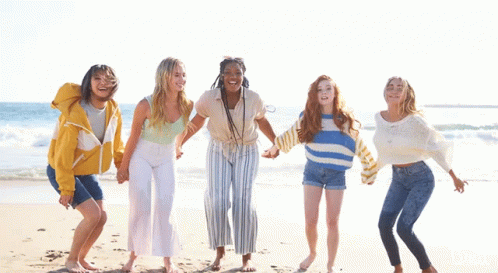 four women holding hands with one another on the beach