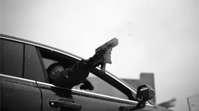 a man holding a hat and a cell phone, sitting on the window of a car