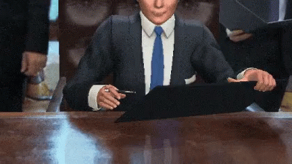 a man in a blue suit sits at a desk