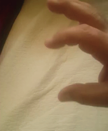fingers on the edge of a white bed spread