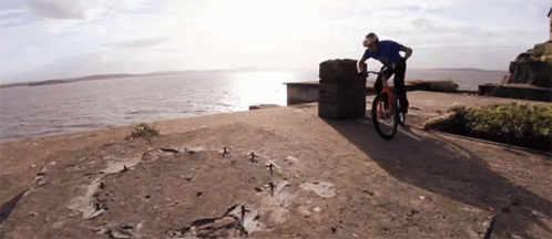 a person riding a bike on a concrete slab by the ocean