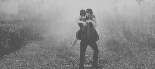 two people are hugging under a rain shower