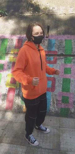 a woman with a blue hoodie on standing near some graffiti