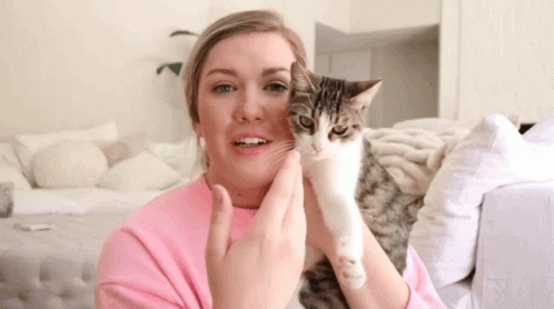 the girl is smiling while holding her cat