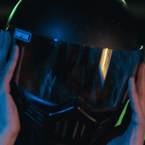 person wearing a welding helmet and holding the inside of his helmet
