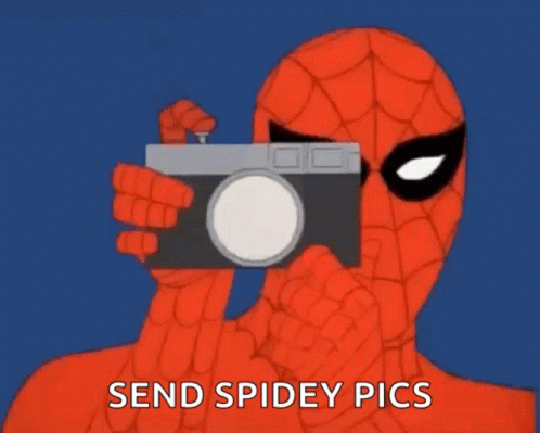 a person holding up a camera and wearing a spider suit