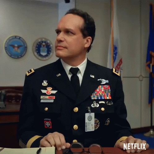 a blue man dressed in uniform is sitting at his desk