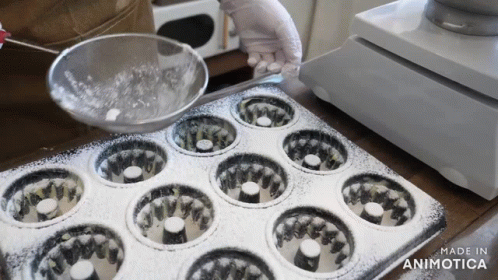 a baker is placing muffin pans in the middle of a counter top
