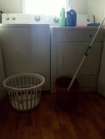 a laundry basket and bucket sit near washers in the room