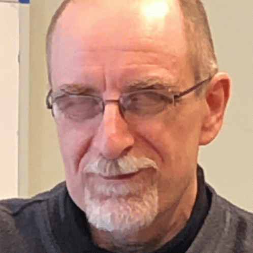 an older man with glasses looks at the camera