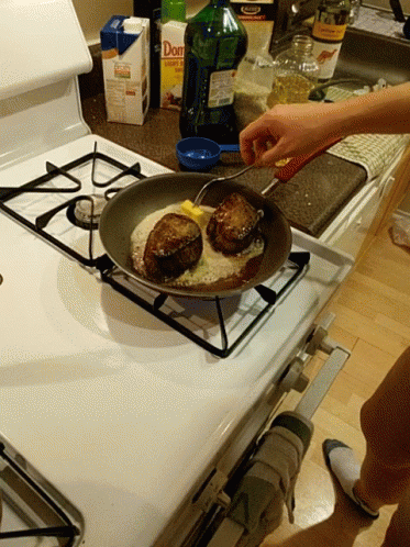 someone in blue gloves frying three cakes on a stove