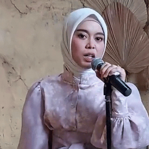 a woman wearing a head scarf holding a microphone