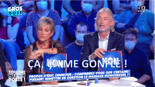 two people sit at a table in front of the audience holding signs