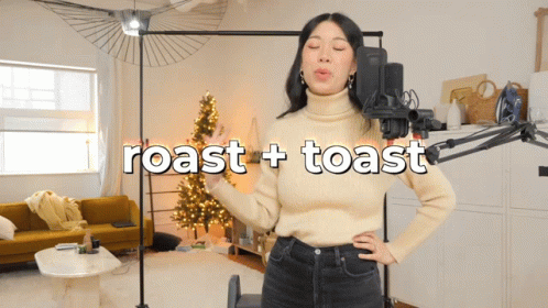 a woman standing with her hands in her pockets and a camera behind her, holding a blue object in her hand, next to the words roast roast and toast