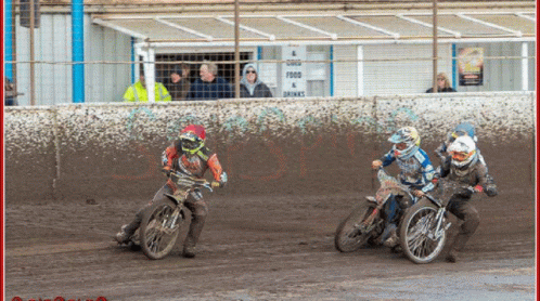 two men riding motorcycles around a dirt track