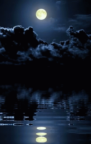 a full moon rising over some water near some clouds