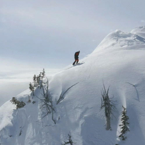 a snow skier descending over a snowy mountain slope