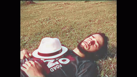 the man is lying on the grass with his hat on