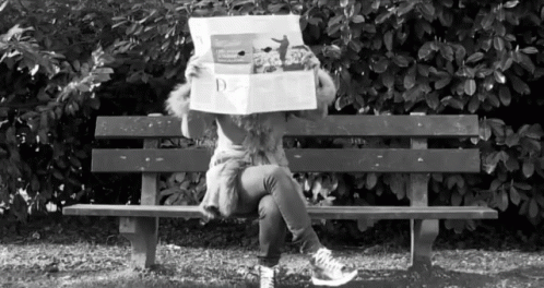 a person is sitting on a bench with a large box on their head