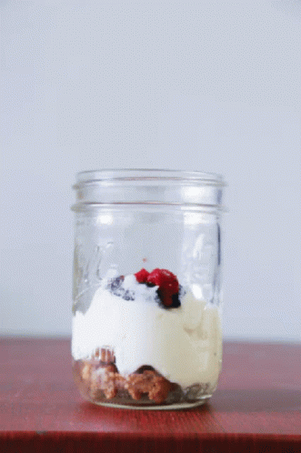 a mason jar with soing in it is filled with ice cream and blueberries
