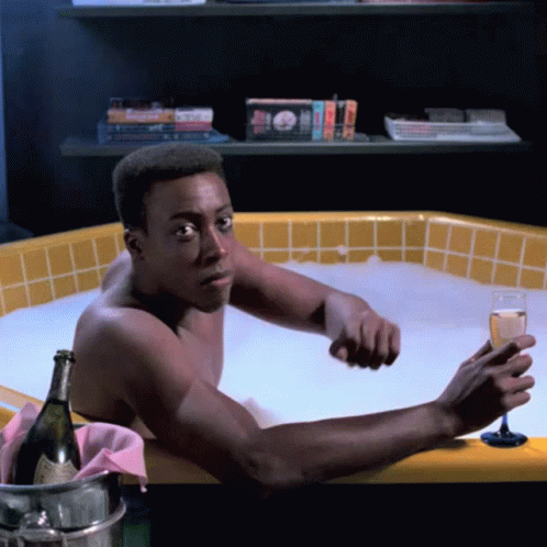 the man is in the bathtub drinking a glass of wine