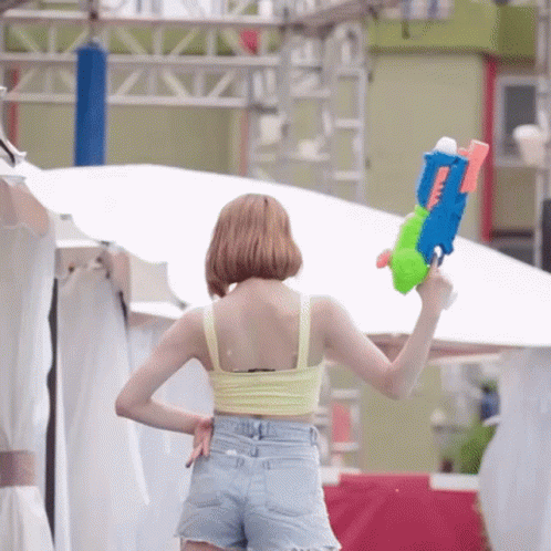 a girl in shorts is holding a plastic gun