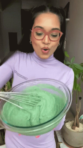 a woman mixing up some green things in a bowl