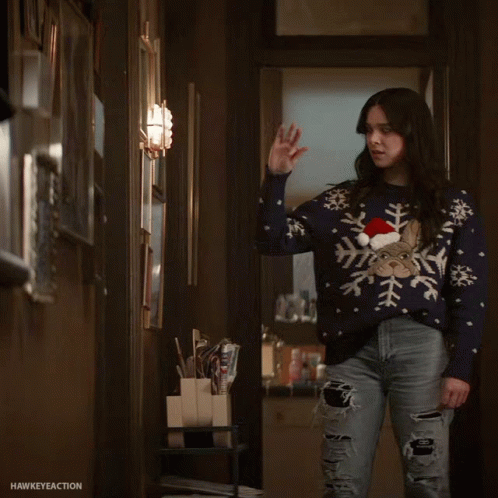 a girl standing in an office doorway wearing snowflake sweater