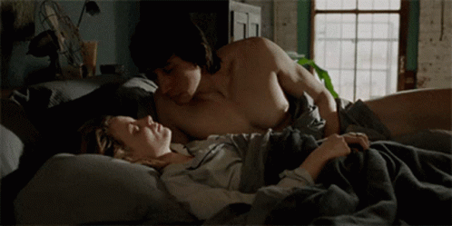 two shirtless men lying in a bed next to each other