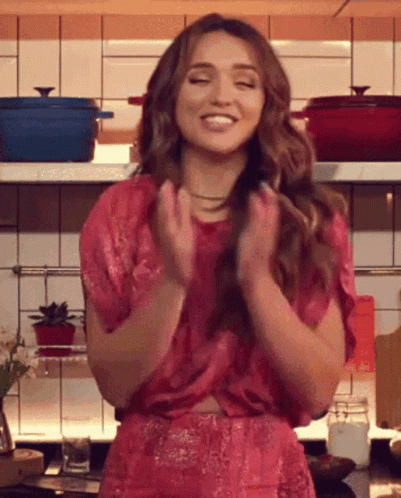 a girl standing in the middle of a kitchen clapping